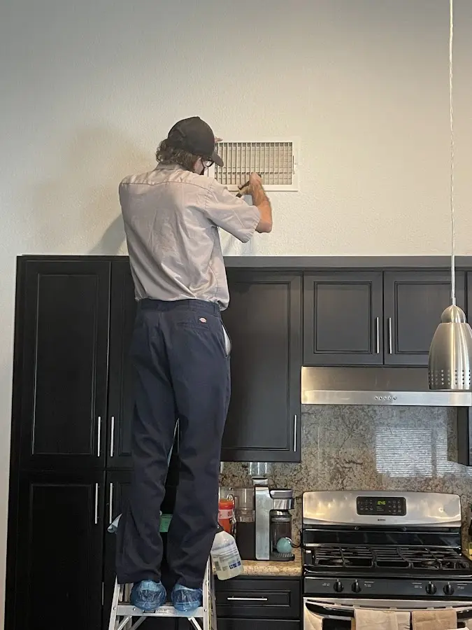 Technician inspecting an air vent during HVAC service in Leawood